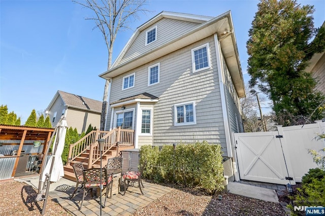 rear view of property with fence, a patio area, and a gate