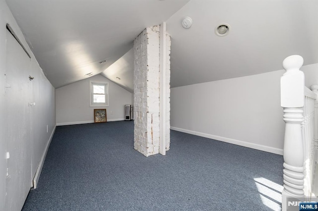 additional living space with carpet flooring, radiator heating unit, vaulted ceiling, and baseboards