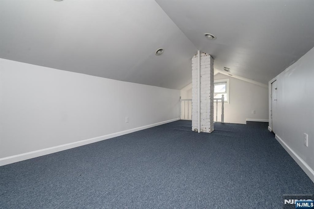 bonus room with dark colored carpet, lofted ceiling, and baseboards