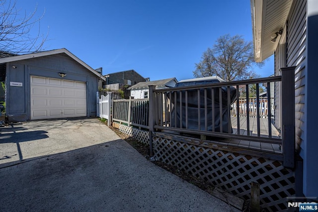 exterior space featuring a deck, an outdoor structure, a detached garage, and concrete driveway