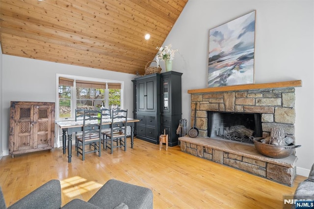 living area featuring high vaulted ceiling, hardwood / wood-style flooring, a stone fireplace, and wooden ceiling