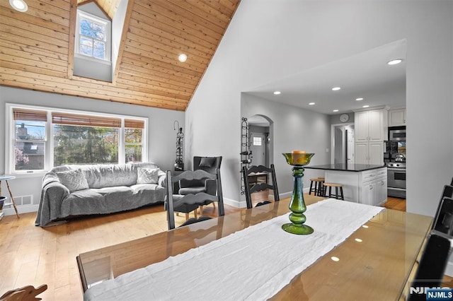 living room featuring recessed lighting, arched walkways, high vaulted ceiling, and light wood-style flooring