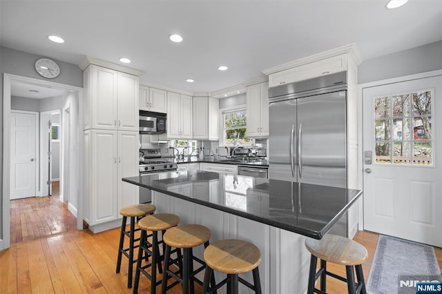 kitchen featuring a breakfast bar, white cabinets, light wood-style floors, and appliances with stainless steel finishes
