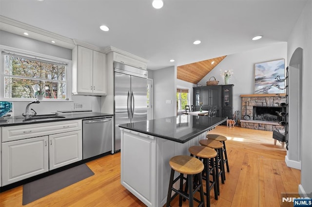 kitchen with a sink, stainless steel appliances, a kitchen breakfast bar, a center island, and white cabinets