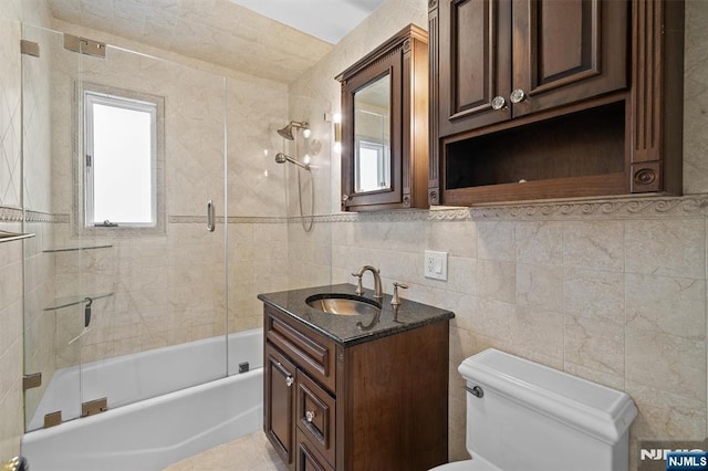 full bathroom with tile walls, washtub / shower combination, toilet, and vanity