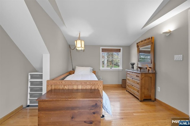 bedroom featuring light wood-style flooring, vaulted ceiling, and baseboards