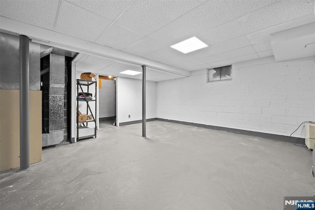 basement with a drop ceiling and baseboards