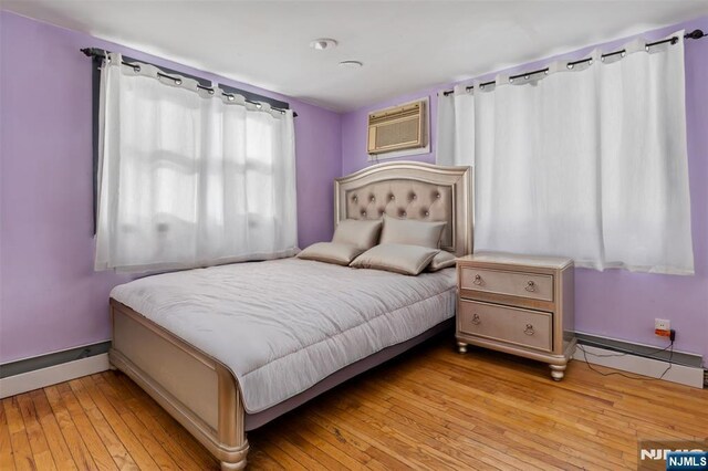 23 Foundry St, Newark, NJ 07105 - bedroom featuring light wood-style flooring, baseboards, a wall mounted AC, and a baseboard radiator