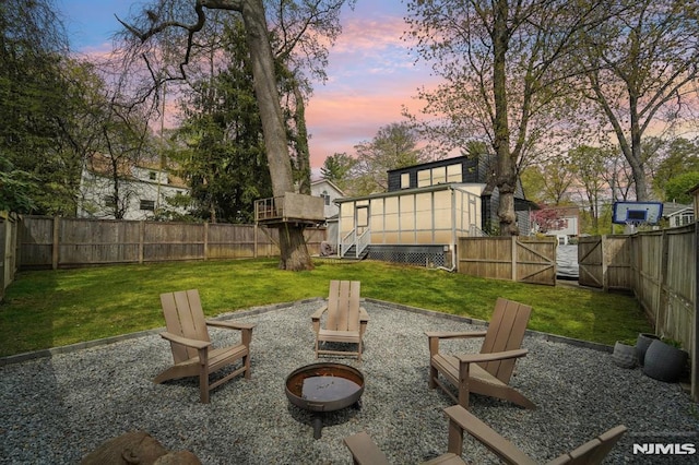 view of yard featuring a sunroom, a fenced backyard, and an outdoor fire pit
