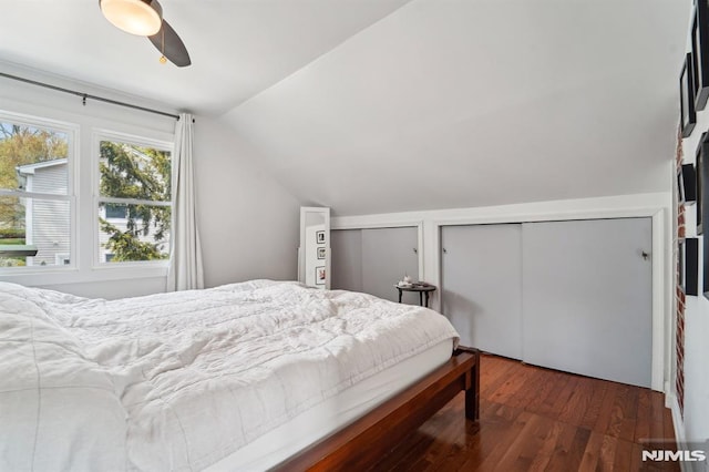 bedroom featuring two closets, ceiling fan, wood finished floors, and lofted ceiling