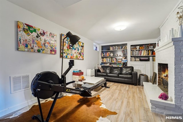 interior space featuring a brick fireplace, visible vents, and wood finished floors