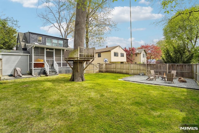 view of yard featuring a fenced backyard, a sunroom, and an outdoor fire pit
