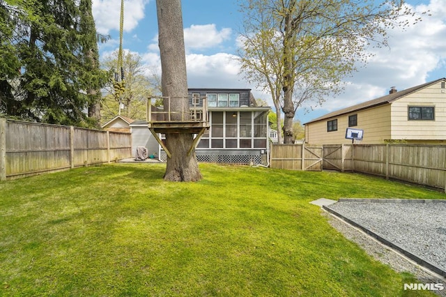 back of house featuring a sunroom, a fenced backyard, and a lawn