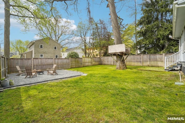 view of yard with a fire pit, a fenced backyard, and a patio area