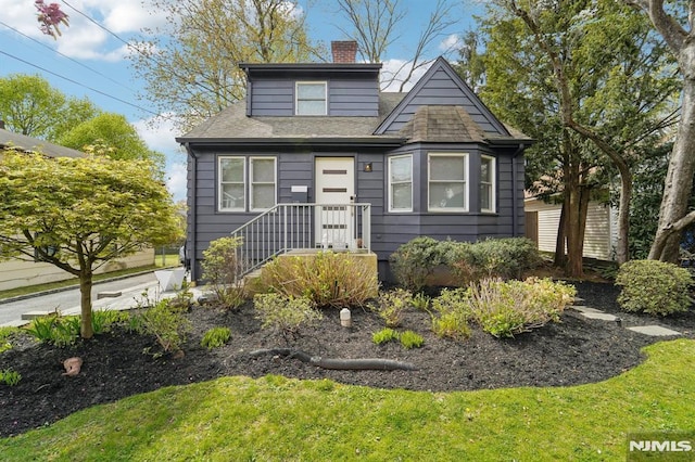 bungalow with a shingled roof and a chimney