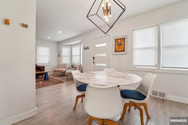 dining room featuring an inviting chandelier, baseboards, wood finished floors, and visible vents