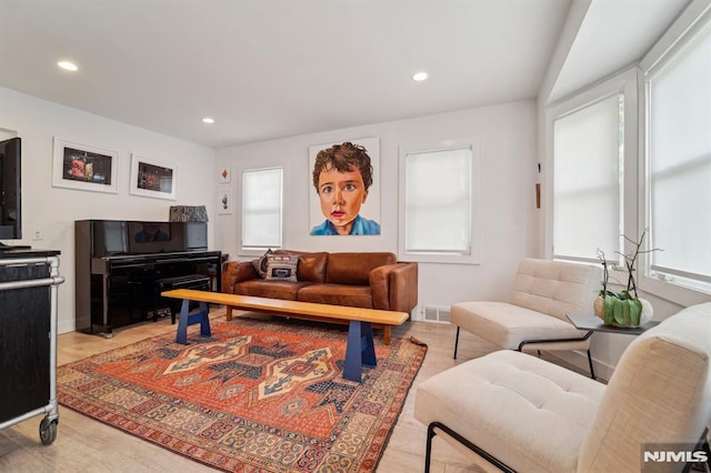 living room featuring baseboards, light wood finished floors, recessed lighting, and visible vents