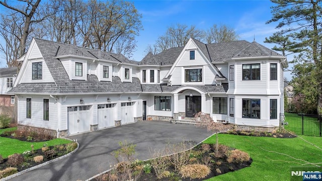 shingle-style home featuring fence, a front lawn, aphalt driveway, and an attached garage