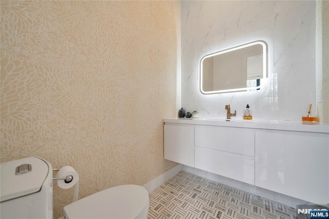bathroom featuring toilet, wallpapered walls, and vanity