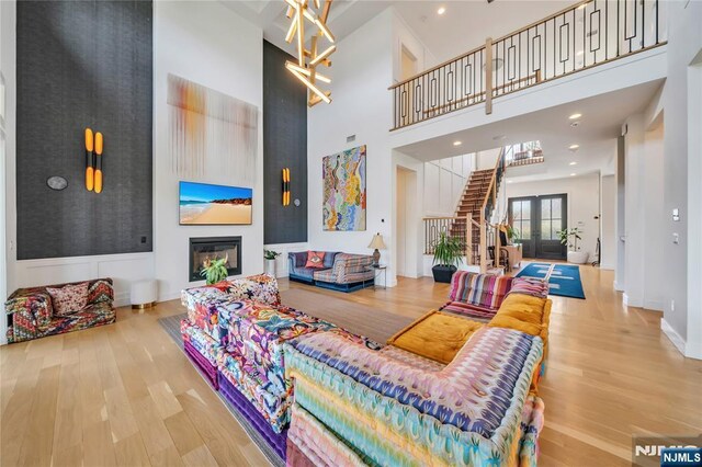 living room with wood finished floors, a fireplace, baseboards, stairway, and a towering ceiling