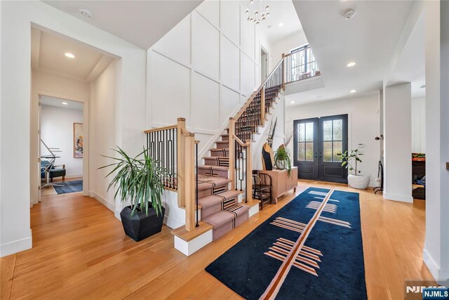 foyer entrance with recessed lighting, a high ceiling, stairway, wood finished floors, and french doors