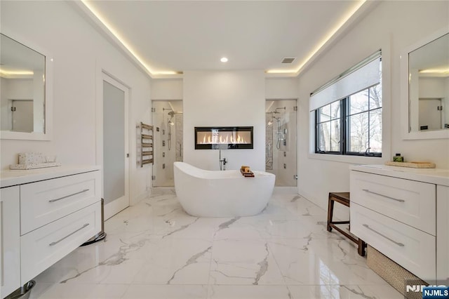 full bathroom featuring recessed lighting, a freestanding tub, vanity, visible vents, and a stall shower