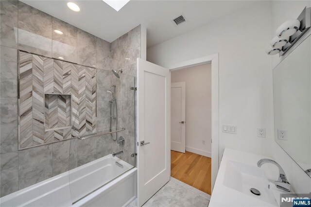 full bathroom with wood finished floors, shower / tub combination, a sink, baseboards, and visible vents