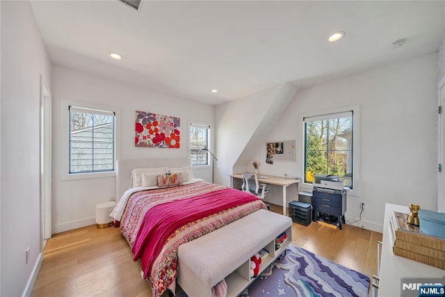 bedroom with baseboards, light wood finished floors, and multiple windows