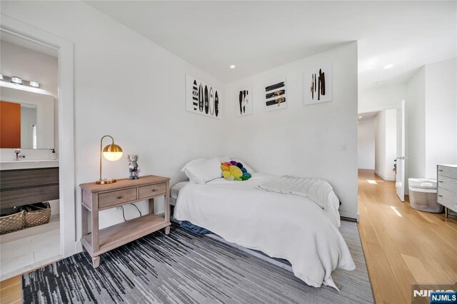 bedroom with wood finished floors, ensuite bathroom, and recessed lighting