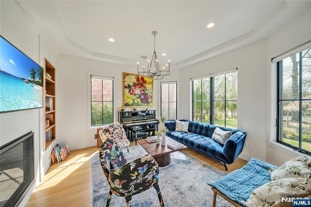 living room with a wealth of natural light, a chandelier, and a tray ceiling