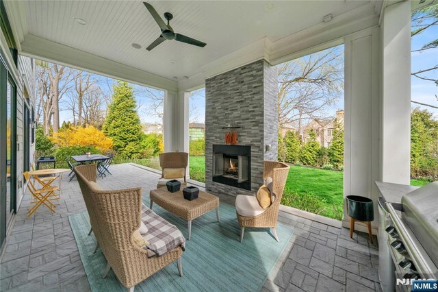view of patio / terrace with a ceiling fan, an outdoor stone fireplace, and grilling area