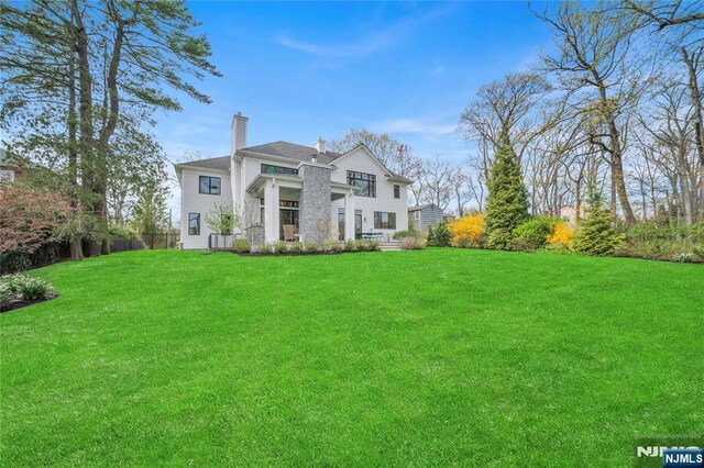 back of property featuring a lawn and a chimney