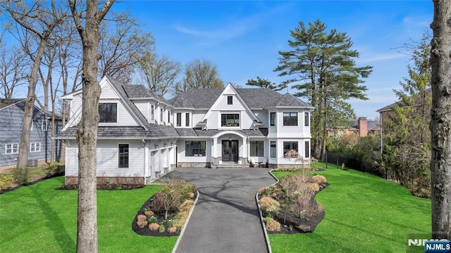 shingle-style home featuring aphalt driveway and a front lawn