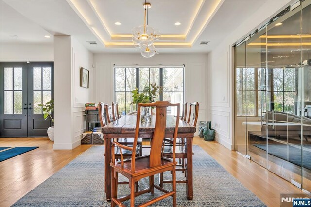 dining space featuring a notable chandelier, a healthy amount of sunlight, and a decorative wall