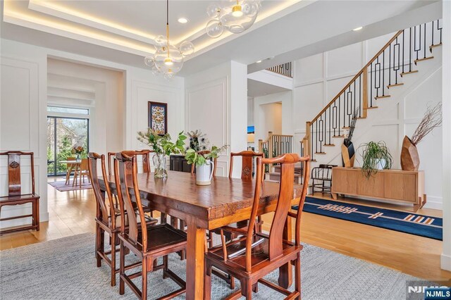 dining space featuring light wood finished floors, recessed lighting, stairway, and a decorative wall