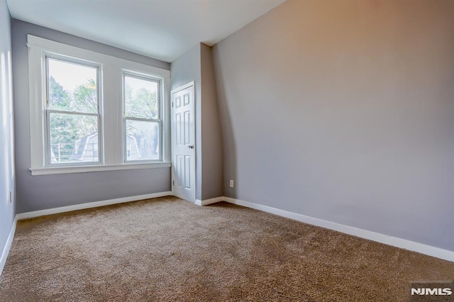 carpeted empty room featuring baseboards