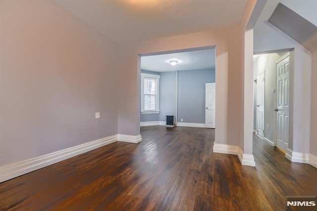 spare room with baseboards and dark wood-style floors