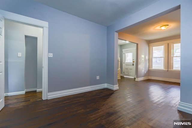 spare room with baseboards and dark wood finished floors