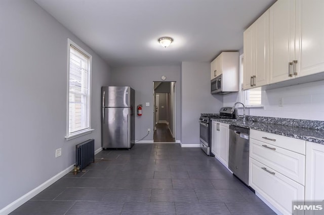kitchen featuring white cabinets, radiator heating unit, stainless steel appliances, and plenty of natural light