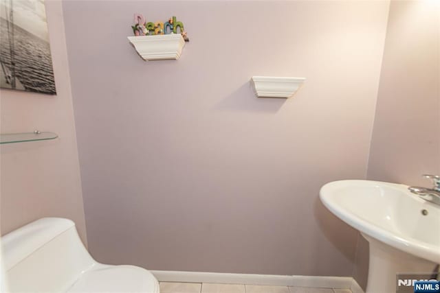 bathroom featuring toilet, tile patterned flooring, a sink, and baseboards