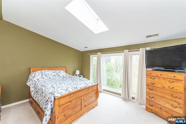 bedroom featuring baseboards, visible vents, light colored carpet, and vaulted ceiling with skylight