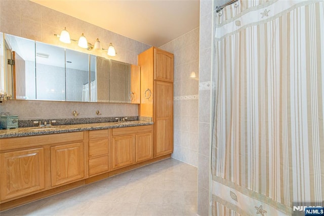bathroom featuring a sink, curtained shower, tile walls, double vanity, and tile patterned flooring
