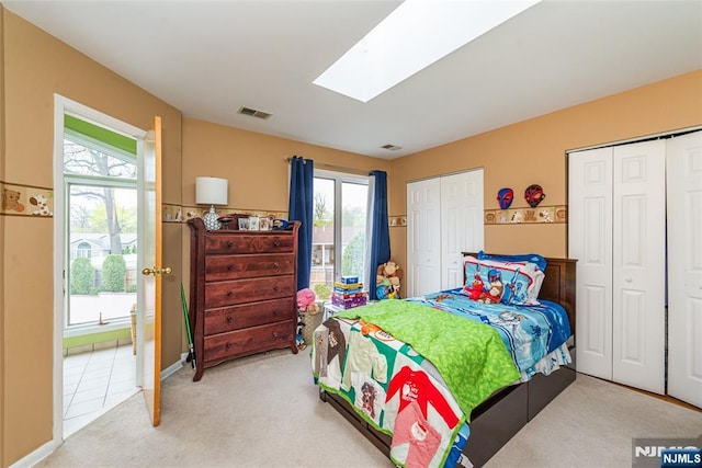 bedroom with a skylight, visible vents, light colored carpet, and multiple windows