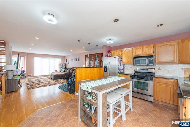 kitchen with recessed lighting, stainless steel appliances, dark countertops, tasteful backsplash, and open floor plan