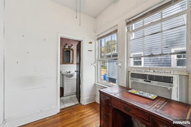 home office with baseboards, a sink, wood finished floors, and cooling unit