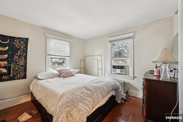 bedroom with cooling unit, multiple windows, baseboards, and dark wood-type flooring