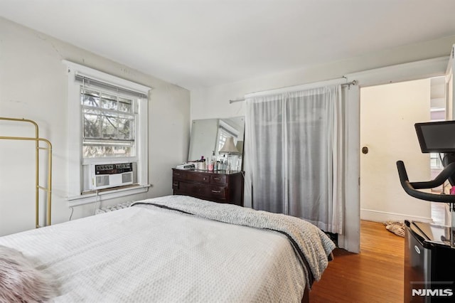 bedroom featuring baseboards, wood finished floors, and cooling unit