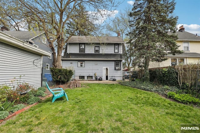 rear view of property featuring a lawn, fence, a chimney, and a patio area