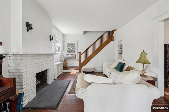 living area with stairway, radiator heating unit, a fireplace, and wood finished floors