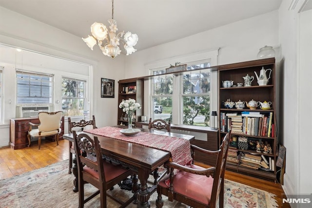 dining room with wood finished floors, a notable chandelier, and cooling unit